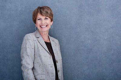 Gabriele Scheibel lehnt an eine Wand und lacht in die Kamera